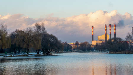 Smoking chimneys of thermal power plants near the waterfront in city. Winter. Industrial and nature background. Ecological concepts.の写真素材