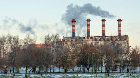 Smoking chimneys of thermal power plants near the waterfront in city. Winter. Industrial and nature...