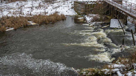 Boiling water in a winter river under a pedestrian bridge. Abstract background. Space for text....