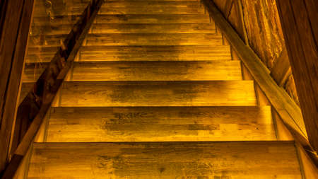 Yellow led light pouring from below onto a wooden staircase. Space for text. Abstract background. Image for design.の写真素材