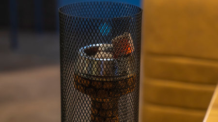 Close-up view of modern hookah with coconut charcoal and shisha smoke. Blurred background. Hot red...
