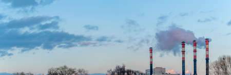 Smoking pipes from factories against a sunset sky. Close-up view of smoking factory chimney. Ecological problem. The chimney pipe emits thick. Global Warming.の写真素材