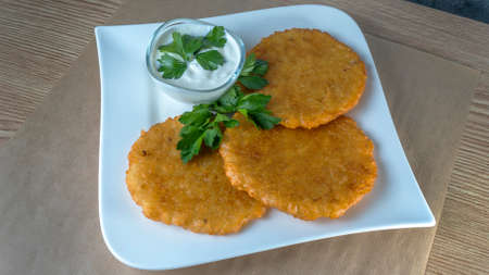 Close-up view of fried potato pancakes with cream sauce and leaf of parsley. Slavic cuisine...