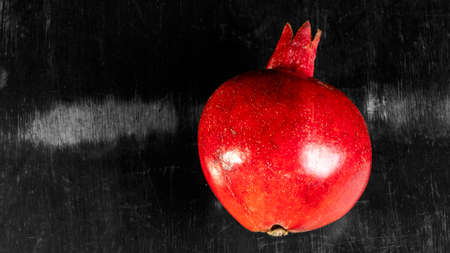 On the table lay red pomegranate. Ripe garnet on the table on black and white wooden background. Still life concept.の写真素材
