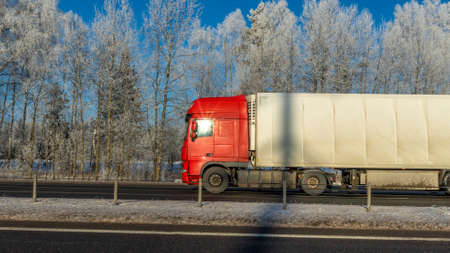 Truck goes on winter road. Van in the road of winter. Lorry car and cold landscape. Roadway and route snowy street trip. Winter road transportation truck. Logistic concepts.の写真素材