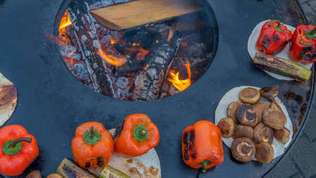 Cooking grilled vegetables on a street stove during the fair. Sale of grilled food at the festival. Festive street food background.の写真素材