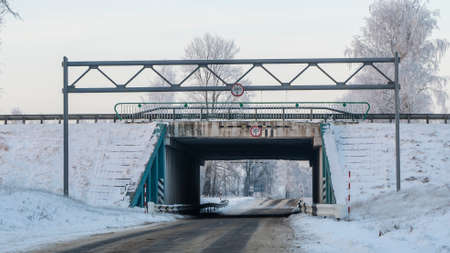 Outdoor scenery of empty street pass through small tunnel under highway and agriculture field covered by snow in winter. Space for text.の写真素材