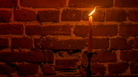 Candle flame close-up on a red wall background. Melted Wax Candle light border design. long exposure. Darkness. Burning at Night, Candlelight. widescreenの写真素材