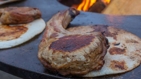 Tomahawk Steak being grilled on the charcoal grill. Grilled steak on the bone. Flat lay, street food concept. Grilling a thick tomahawk ribeye chop steak steak on an outdoor backyard garden grill.の写真素材