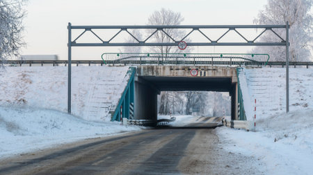Outdoor scenery of empty street pass through small tunnel under highway and agriculture field covered by snow in winter. Space for text.の写真素材