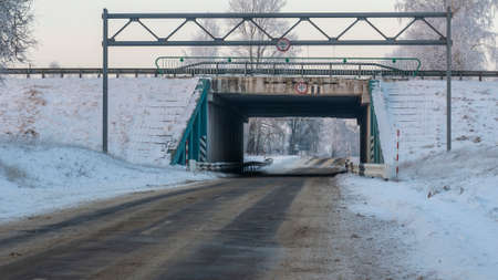 Outdoor scenery of empty street pass through small tunnel under highway and agriculture field covered by snow in winter. Space for text.の写真素材