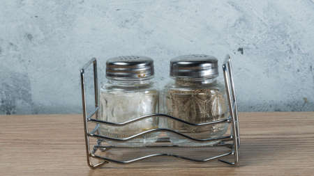 Modern Salt and Classic pepper grinders standing on wood texture table. Salt and pepper shaker on...