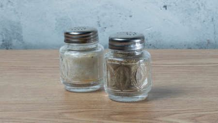 Modern Salt and Classic pepper grinders standing on wood texture table. Salt and pepper shaker on...