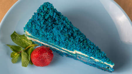 Blue cake with strawberry and leaf of mint on light blue plate. top view. The concept of Holiday desserts for a birthday. Space for text.の写真素材