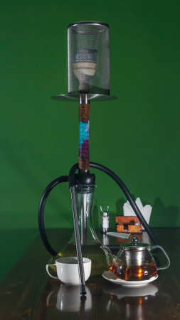 Traditional Arabian shisha and tea with lens flare. A pot of tea and smoking hookah on a dark green background. Stylish hookah and tea kettle. Lounge concept. Space for text.の写真素材