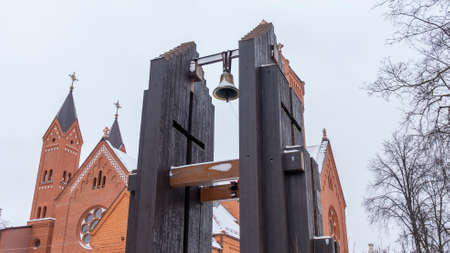 Church over cloudy gray sky. Belfry with a bell against the background of a red church. Worship concepts. Space for text.の写真素材