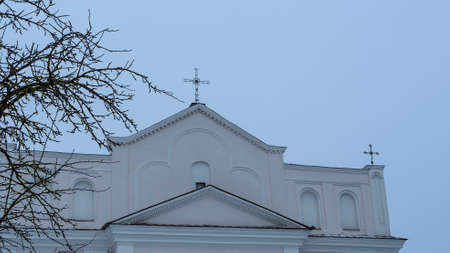 Catholic church roof with cross through bare branches of the tree. View of dome of old catholic chapel. Religion concepts.の写真素材
