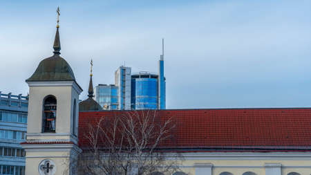 Old orthodox cathedral against the blue sky and high rise modern buildings background. ancient vs. modern. Space for text. Religion concepts.の写真素材