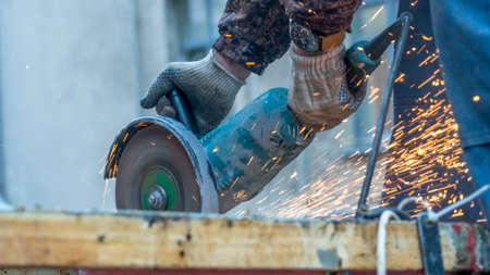 Close-up view of a worker working with angle grinder. Electric wheel grinding on steel structure....