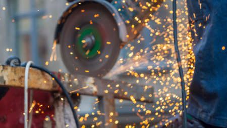 Defocused close-up view of a worker working with angle grinder. Electric wheel grinding on steel...