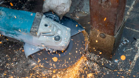 Close-up view of a worker working with angle grinder. Electric wheel grinding on steel structure....