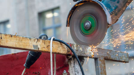 Close-up view of a worker working with angle grinder. Electric wheel grinding on steel structure. Sparks. Angle grinder at work, sparks and dust from the cut-off steel pipe.の写真素材