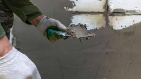 Plastering cement at wall for renovation house. Plasterer smoothing plaster on wall. putty brick...