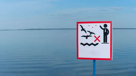 Sign over water to not feed the birds. Do not feed the animals wildlife birds sign with copy space on water background. Wildlife and healthcare concepts.の写真素材