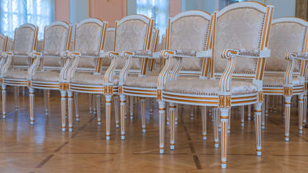 Row of luxury vintage chairs. Chairs for seating the audience at the conference or concert. Theatrical armchairs. Upholstered bejie textile seats in the auditorium.の写真素材