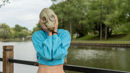 A girl in a gas mask shows fear with her hands. alienation in the city. Fashion, ecology and loneliness concepts. Coronavirus. ecological and epidemic problems.の写真素材
