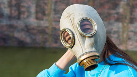 A girl in a gas mask sits by the fountain. alienation in the city. Fashion, ecology and loneliness concepts. Coronavirus. ecological and epidemic problems.の写真素材
