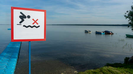 No Diving sign at beach, lake Naroch, Belarus. Warning sign of shallow water. Warning notice sign do not jump in water. No Diving sign near the plastic pier.の写真素材