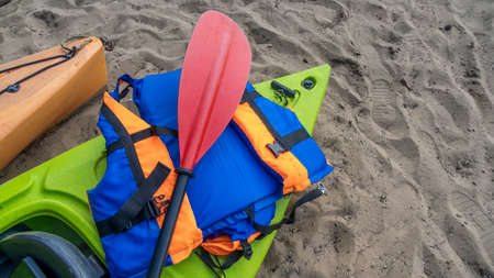 Camping with kayaks on the beach of the river on a sunny day. Modern kayaks with paddles on the beach near the river. summer camp activity. travel concepts.の写真素材