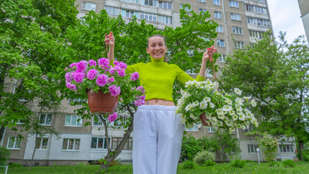 The attractive woman holding decorative petunia flower in flower pot on the street. gardening and planting. Concept of garden and interior decoration.の写真素材