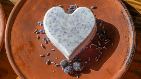 Homemade lavender ice cream in the shape of a heart in rural clay plate decoration blueberry. Creamy vegan lavender ice cream. Provence style. Space for text.の写真素材
