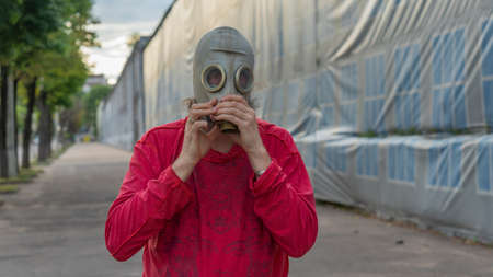 Strange man in a gas mask standing on the street in an empty city. Man wearing anti-pollution, anti-smog and viruses face mask. Man in a chemical gas mask posing on the street.の写真素材