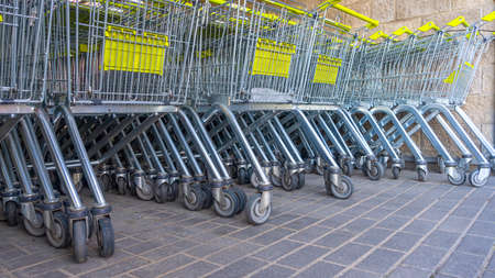 Many metal shopping carts on a parking lot near supermarket outdoors. shopping concept. Shopping carts outside. Shopping carts in parking lot. Set of supermarket trolleys on mall parking lot.の写真素材