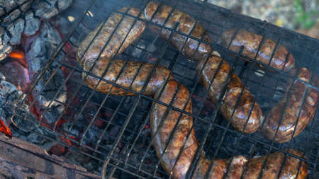 Tasty homemade sausage made of beaver meat cooking on grill. Beaver meat sausages are cooked on coals. Homemade beaver sausages.の写真素材