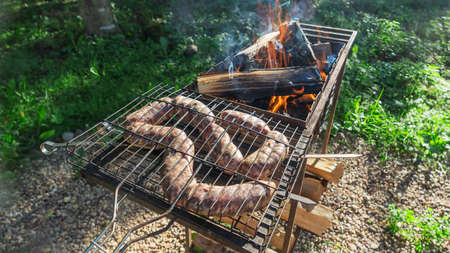 Tasty homemade sausage made of beaver meat cooking on grill. Beaver meat sausages are cooked on coals. Homemade beaver sausages.の写真素材