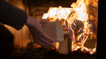 Eco-friendly compressed wood briquettes ignite a warm, inviting fire in a modern stove, showcasing sustainable heating and cozy ambiance for any homeの写真素材