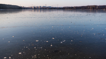 Delicate ice forms on the lake's surface as spring arrives, showcasing intricate patterns of melting. This serene scene captures the beauty of nature's transition from winter to spring.の写真素材