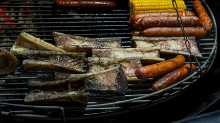 Sizzling sausages and sweet corn grilling over an open flame, creating a mouthwatering feast. Perfect for summer barbecues, this vibrant scene captures the essence of outdoor cooking and enjoyment.の写真素材