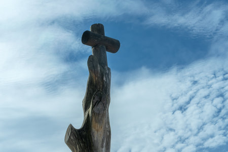 Sacred Wooden Cross Carved from Tree Trunk Under Dramatic Sky. Carved Catholic Cross on Tree Trunk Against Dramatic Sky.の写真素材