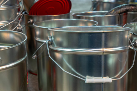 Rows of empty tin cans prepared for vibrant paint production. Empty vessels awaiting paint. Empty tin cans lined up in a paint factory. Rows of empty paint cans in an industrial setting.の写真素材