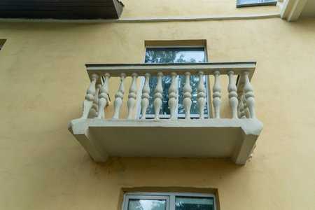 A balcony on a building with a railing, showcasing urban architecture and the tranquility of a serene space. The image evokes curiosity and contemplation, symbolizing solitude and the quiet strength of a home.の写真素材