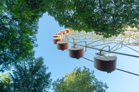 Ferris Wheel And Green Trees Against Blue Sky. Summer Amusement Park Scene With Ferris Wheel Rising...