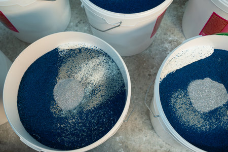 Production of decorative plaster at the factory. Materials for repair and decoration. Closeup of blue decorative plaster mixture in a bowl showcasing texture and contrast.の写真素材