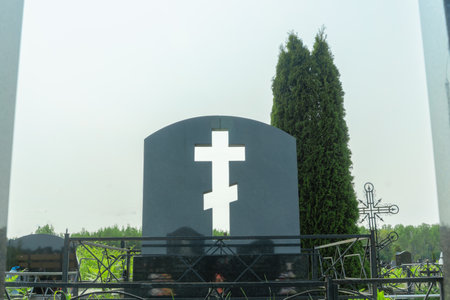 Tombstone with a cross cut through symbolizing faith in a peaceful cemetery. Light streaming through the cross cut in the tombstone illuminating hope and remembrance in a serene graveyard.の写真素材