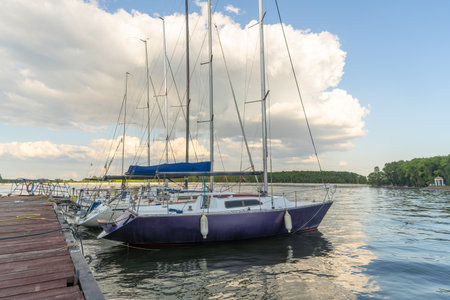 Sailboats docked at quiet marina under clear blue sky. Yachts moored quietly in the harbor, poised for new journeys beneath an endless sky of freedom and possibility.の写真素材