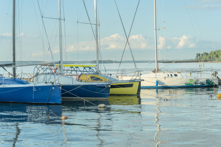 Sailboats docked at quiet marina under clear blue sky. Yachts moored quietly in the harbor, poised for new journeys beneath an endless sky of freedom and possibility.の写真素材
